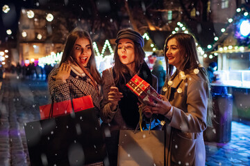 New Year and Christmas. Women friends burning sparklers in Lviv on street fair having fun after shopping with presents.