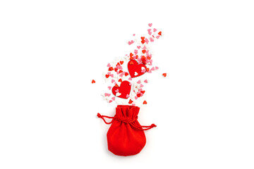 Red gift bag and hearts of different shapes and colors on a light background. The concept of Valentine's Day.