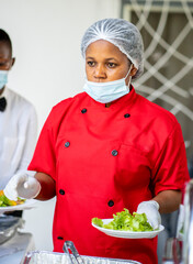 image of african woman, with face mask lowered at the chin, gloves, plate of food- food concept 