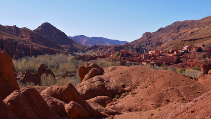 Panorama view of lower Dadès Gorges near Boumalne Dadès, Morocco with red colored rock formations and a Berber village on the foothills of the southern Atlas Mountains on a sunny winter day.