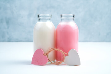 Two bottles of milk drink of different colors and two tied hearts symbolize a couple in love. Side view. The concept of Valentine's day.