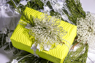 Christmas composition. Gift, fir tree branches, white decoration on yellow  gift box. Christmas, winter, new year concept