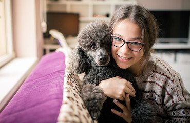 Beautiful girl playing with her dog at home.