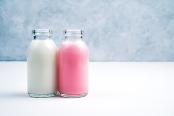 Pink and white milkshakes in bottles on a white and gray background. Side view. Concept of dairy products.
