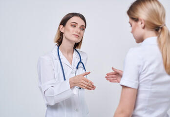 Professional doctor woman shakes hand of a female patient on a light background
