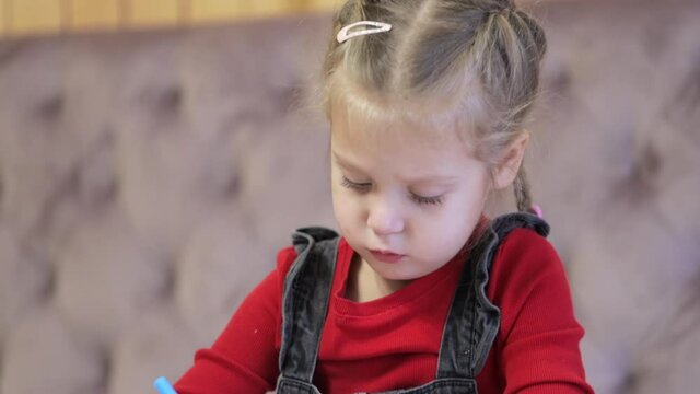 Portrait of a focused preschool girl painting with pencils. Art therapy