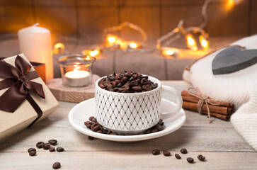 Coffee and gift box on a festive background with a burning garland. Concept of coffee holiday backgrounds.