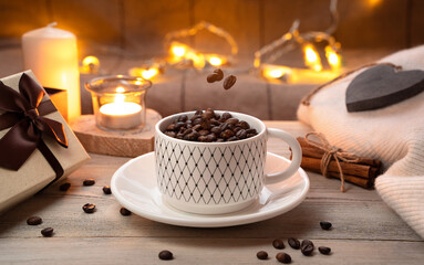 Coffee beans in a Cup and hanging in the air above the Cup on a cozy festive background. Concept of coffee and holidays.