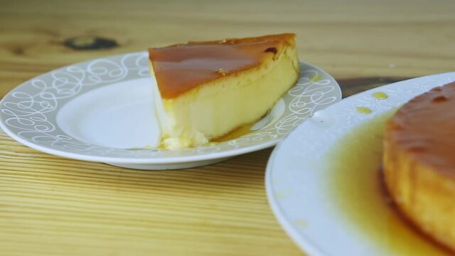 closeup view at piece of homemade soft flan with caramel syrup on round plate