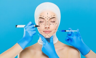 Young woman with ready for plastic surgery procedure, surrounded by doctors with syringe and skin marker, isolated on blue background
