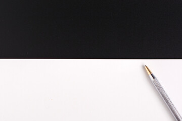 white sheet on black background and silver pen. Copy space