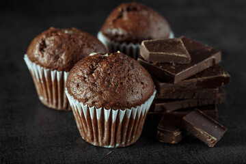 Chocolate cupcake with icing and chocolate bar in Dark lighting,Homemade delicious chocolate muffin on wooden background close-up