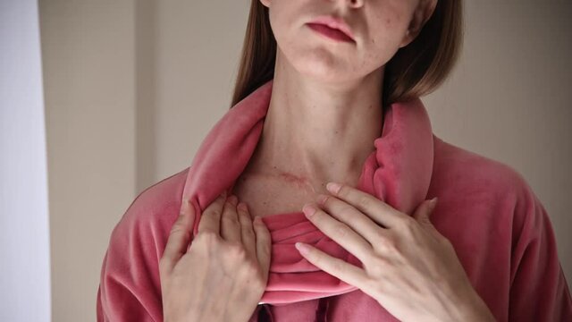 Woman touching surgery scar on her neck.