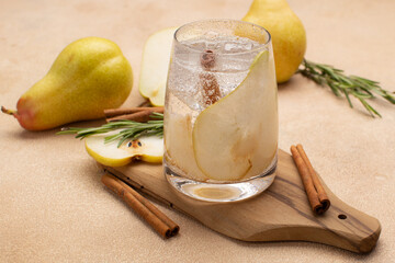 Refreshing pear cocktail with tonic,cinnamon and fresh rosemary on olive wooden board with...
