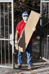 Delivery man with protective mask and medical gloves holding big cardboard delivering box. Express food delivery and shopping online concept. Fast Delivery transport. Quarantine.