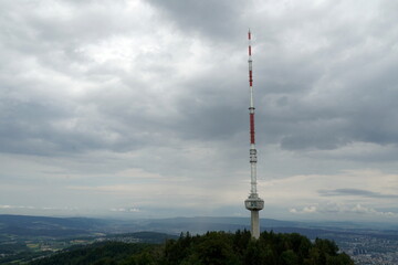 Obraz premium Telecommunication signal emitter or antenna for broadcasting on high placed Uetliberg mountain above Zurich in Switzerland. Summer landscape on on a cloudy rainy day with dramatic sky.