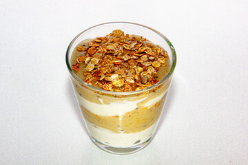 Yogurt with bananas and muesli in a glass Cup on a white background