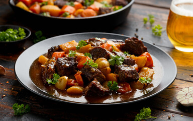 Beef Stew with carrot and baby potato in black plate on wooden table