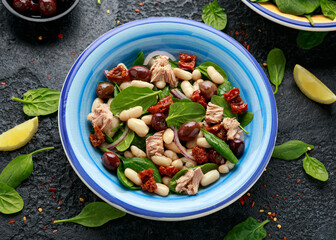 Tuna, white bean salad with olive, red onion, spinach and dried tomato. Healthy food.