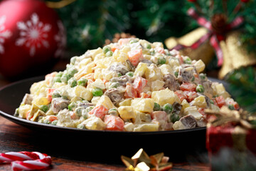 Christmas and New year Olivier salad, traditional Russian food with decoration, gifts, green tree branch on wooden rustic table
