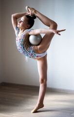 Girl gymnast doing balance exercise with silver ball - obrazy, fototapety, plakaty