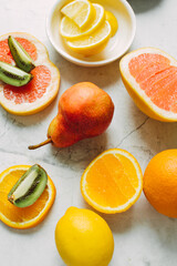 Ripe sliced fruits on a stone background: grapefruit, kiwi, lemon, pear