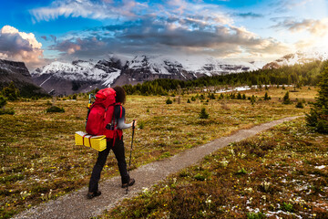 Female Backpacker Hiking in Canadian Rockies. Colorful Sunset Sky Art Render. Taken near Sunshine Village and Banff, Alberta, Canada.