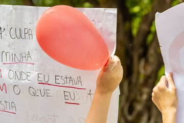 Pessoa segurando cartaz com um balão vermelho. Imagem feita durante uma manifestação em...