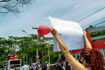 Pessoa segurando cartaz com um balão vermelho. Imagem feita durante uma manifestação em...