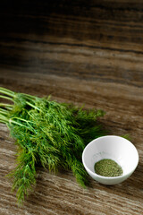 Fresh and dried dill on a wooden board and table