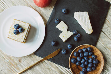 Brie cheese with mold and blueberry and apple on a table