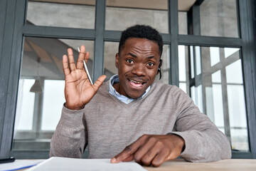 Black businessman, remote teacher wearing headset waving hand talking to camera conference video calling, giving webinar, online class, distance tutoring working at home office, web cam view. Headshot