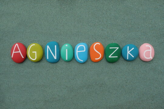 Agnieszka, polish female given name composed with multicolored stone letters over green sand