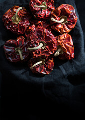 Eight bright red dried peppers on a dark cloth background.
