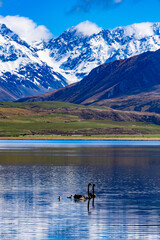 Snow covered mountains and green valleys with a lake in New Zealand