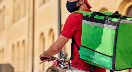 Courier with refrigerator bag on scooter wearing face mask