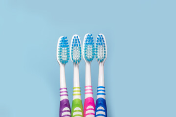 Photo of four multi-colored toothbrush, blue background with copy space, top view. The concept of healthy teeth in the family, tooth care.
