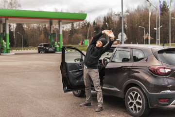 the driver is stretching after a long drive. rest after long driving. stop at a gas station. coffee...
