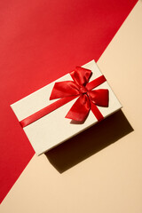 White present with red ribbon on the bright red background