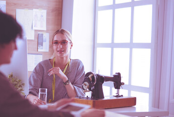 Female dressmaker is communicating with the potential client about custom-made dress in the sewing workshop