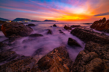 Long exposure image of Dramatic sky seascape with rocks in the foreground sunset or sunrise over sea scenery background.