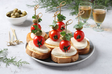 Canapes of mozzarella, cherry tomatoes, green olives, parsley on croutons of white bread on gray background. Festive New Year snack. Closeup