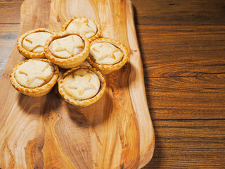 Mince pies on a wooden board and table. Christmas theme snack. Pastry product for special season
