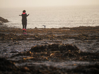 Silhouette of a woman with slim athletic body doing stretch on a beach by an ocean, Ocean in fog in the background. Selective focus. Outdoor workout concept.