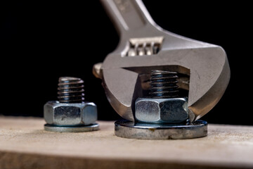 Metal bolts and nuts for joining wood. Tightening the screws with an adjustable wrench.