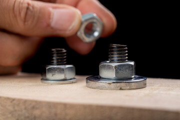 Metal bolts and nuts for joining wood. Tightening the screws with an adjustable wrench.