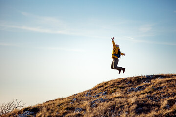 Happy female hiker jumping on the mountain
