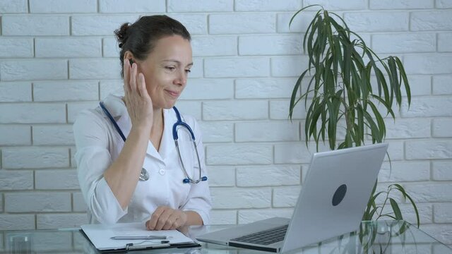 Work in hospital online. A nice smiling doctor in a white coat listen and speak about patient symptoms online. A concept of telemedicine and medical assistant on distance.