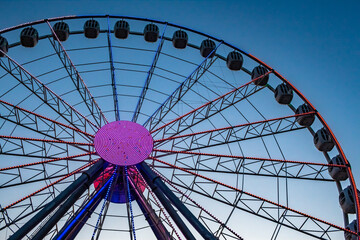 Illuminated ferris wheel against blue sky