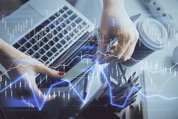 Double exposure of businesswoman hands typing on computer and financial graph hologram drawing. Stock market analysis concept.